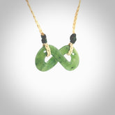 This piece is a fine, delicate eternity shaped pendant. It was carved from a lovely green piece of British Columbian jade. It is suspended on an oat coloured cord that is length adjustable.